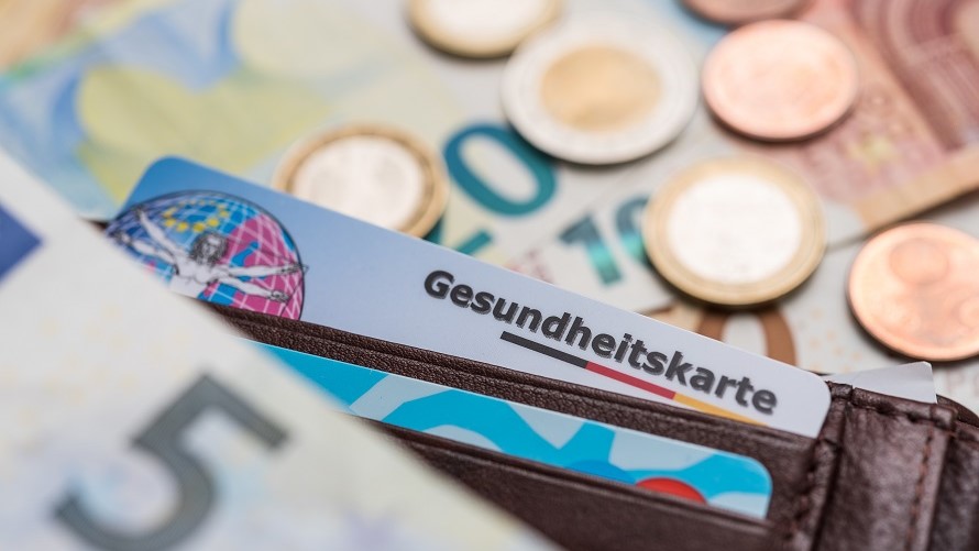 Gesundheitskarte und Geld Geldbörse mit Gesundheitskarte und ausgeleertem Münzgeld und Geldscheinen auf Tisch